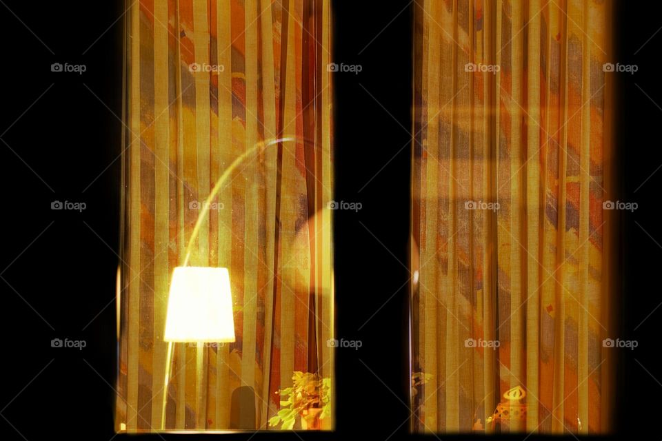 Close-up of my window in the evening from outside with illuminated lamp and orange curtains