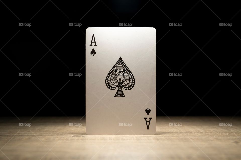 A portrait of the black ace of spades surrounded by darkness with a spotlight only lighting the playing card.