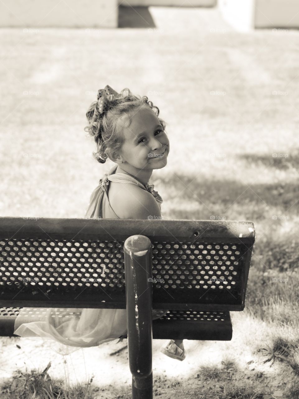 Side view of little girl sitting on metal bench