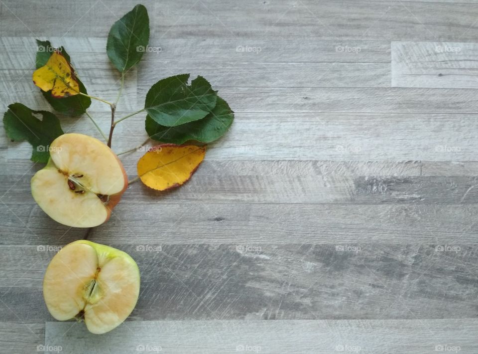 Grey wooden background with apple and leaves.