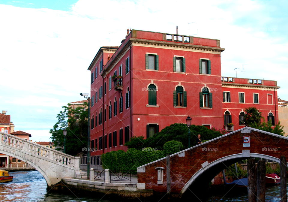 red house next to a bridge and a canal in Venice.