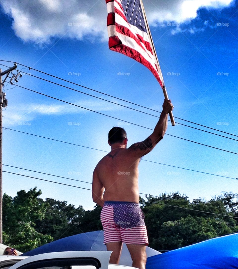 American pride at its finest. Man sporting patriotic shorts and holding American flag
