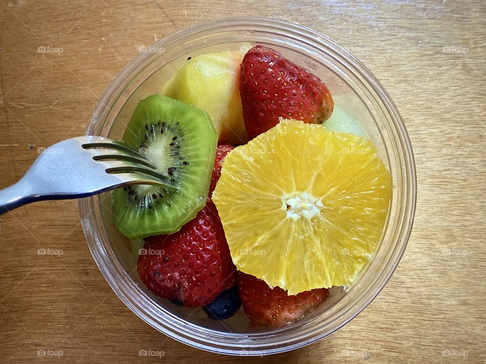 Mixed of Fruits inside the container against brown background.