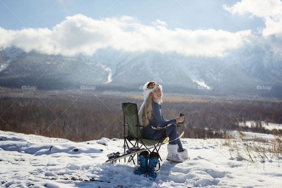 Smiling woman sitting on chair in snowy landscape