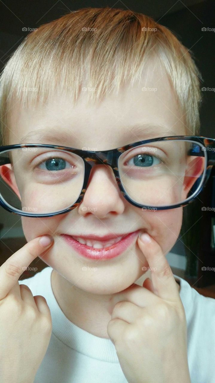 blue eyed boy wearing mommy's glasses