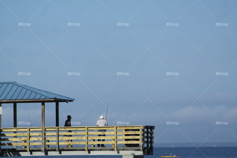Fisherman standing on pier with rod