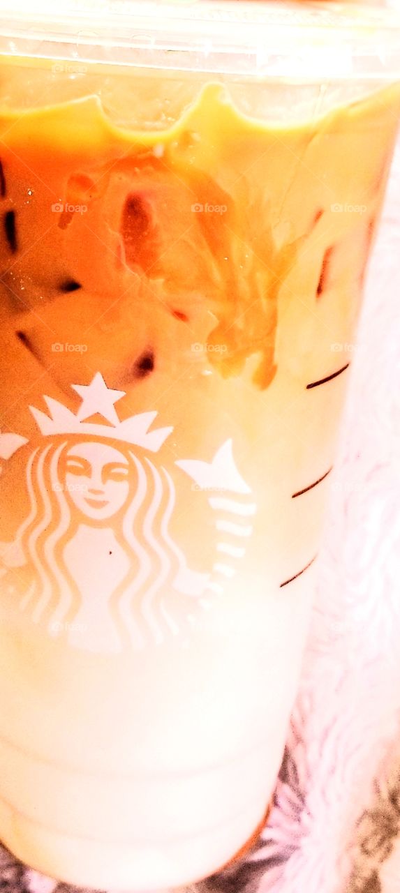 Swirled blend of sweetness of a Caramel Macchiato with accent of white Starbucks logo, drenched in creeping caramel drizzle showing the beautiful white, brown, and golden mix.