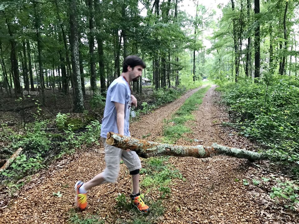 Young handicapped man moving fallen limb to clear drive.