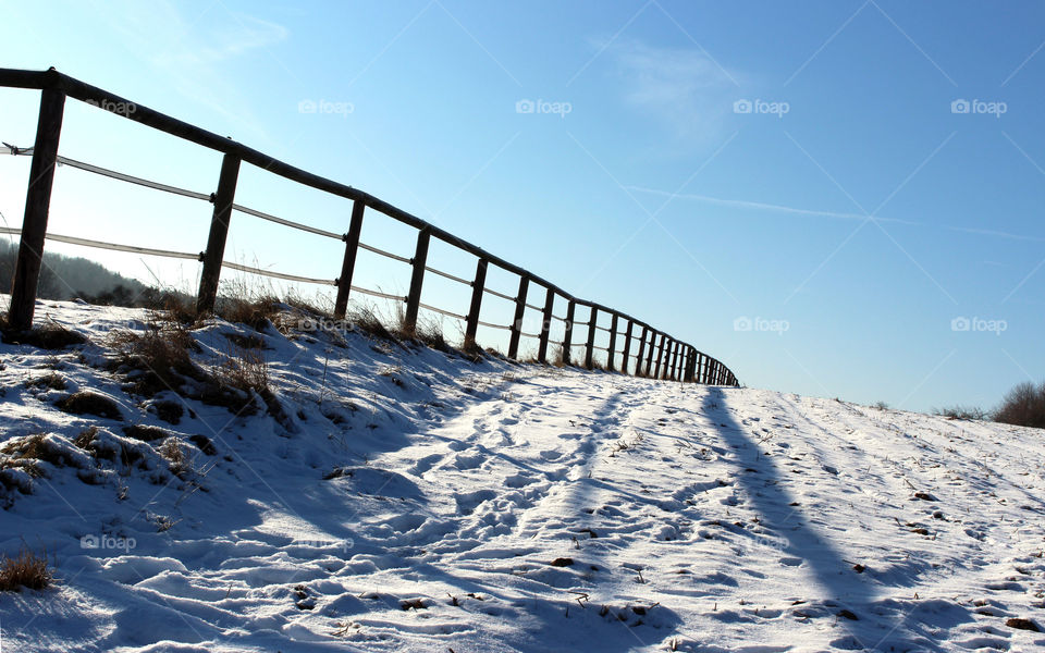 wooden fence at a horse Pasture in snow and sunlight