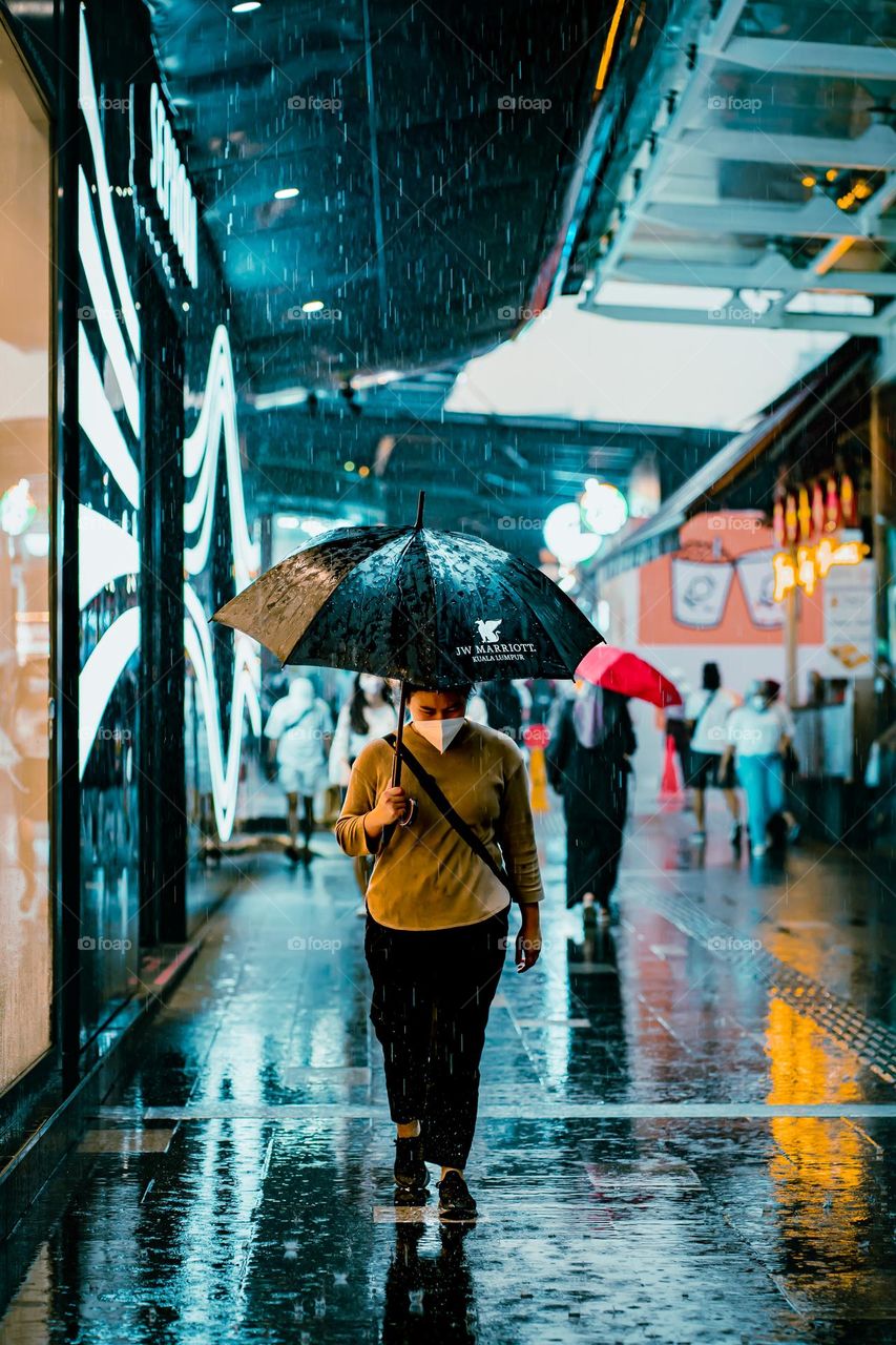 A woman walking in the rain using umbrella