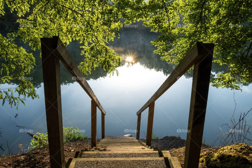 The reflection of the early morning sun just peeking over the horizon viewed from the top of some stairs at Grundy Lakes Park, part of the South Cumberland State Park system, in Tracy City Tennessee.