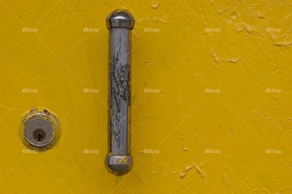 A yellow locked street level building door with security lock and handle in Brooklyn, New York City.