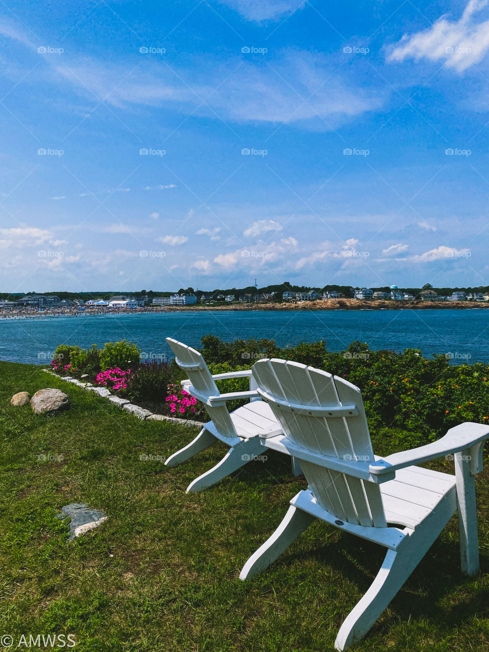 Two white chairs by the ocean. 