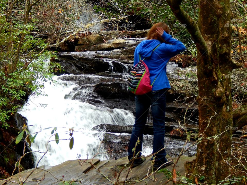 girl standing on boulder admiring pig pen waterfall in South Carolina mountains