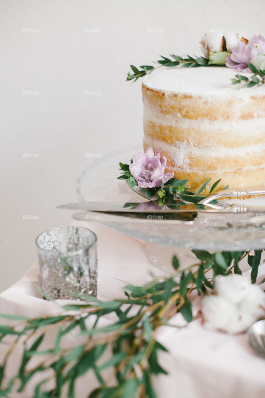 Beautiful wedding round cake with floral decorations on glass cake stand.