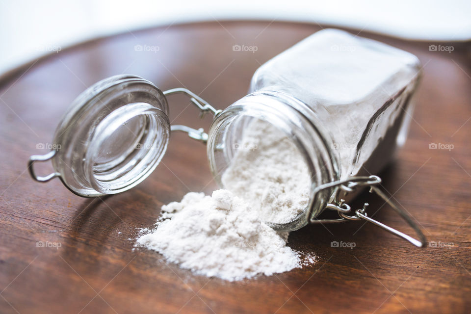 Open jar with flour on a wooden table