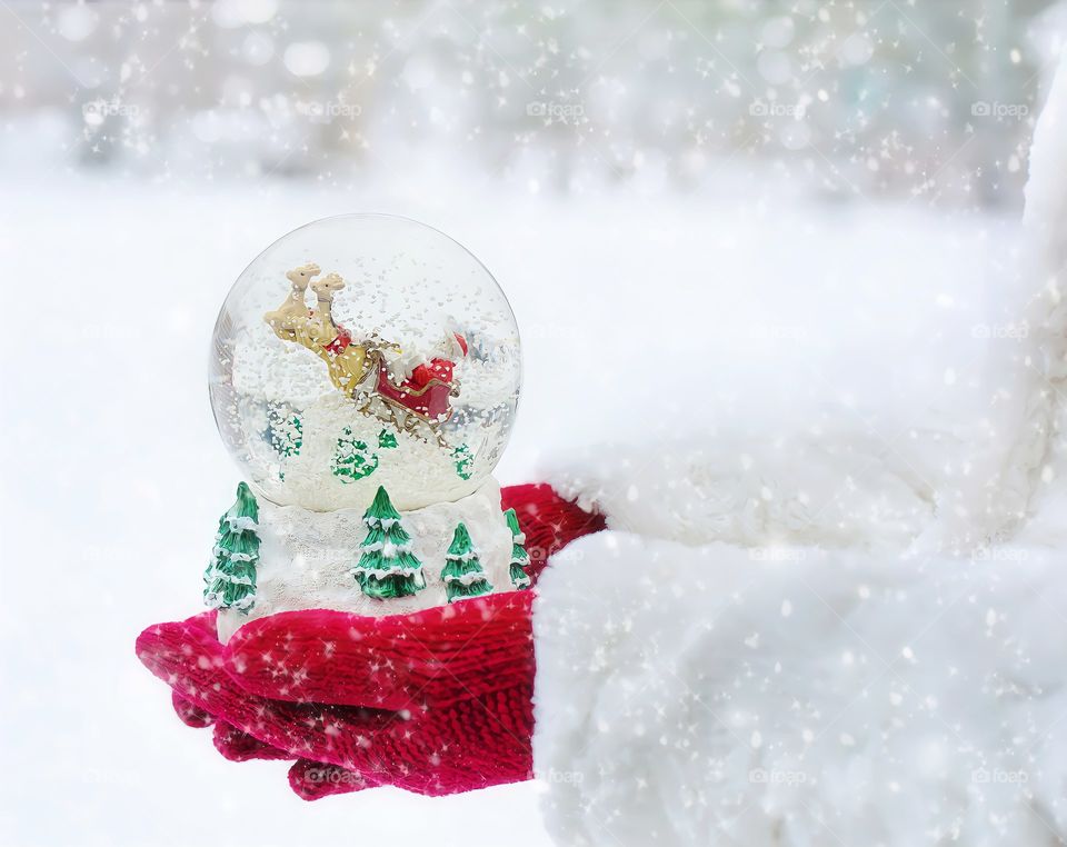 Snow globe and hands in snow
Close up of Christmas snow globe in red gloves hands in snowfall.