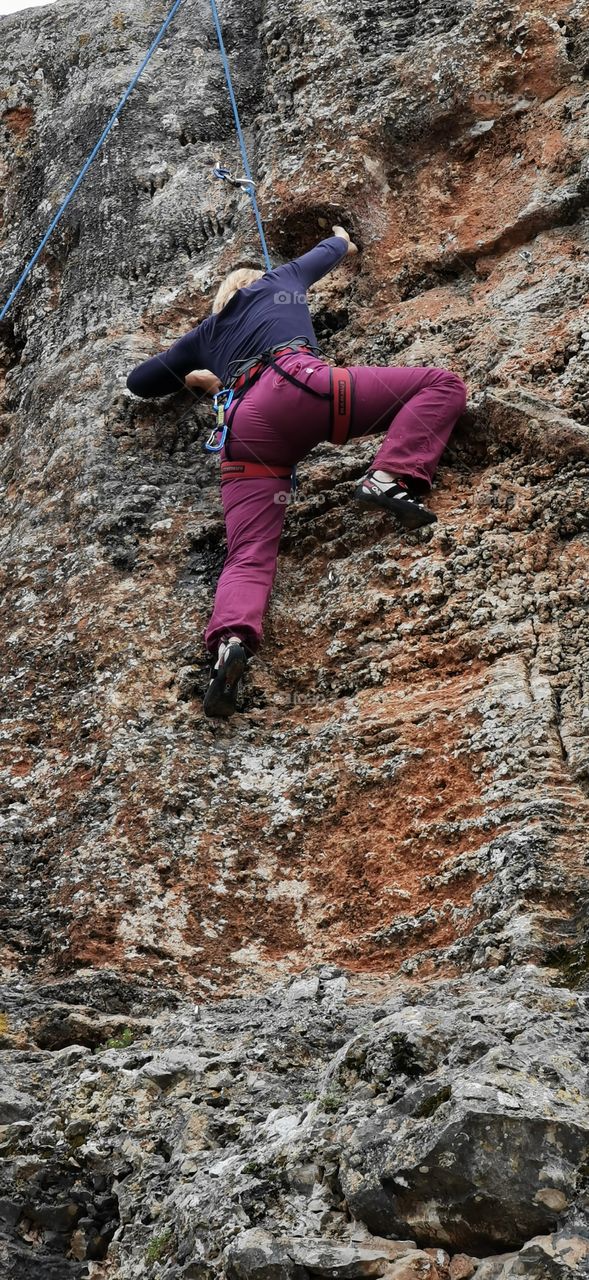 Fast oben angekommen. Eine Frau klettert den Steinbruch nach oben und hält sich an einem Vorsprung fest