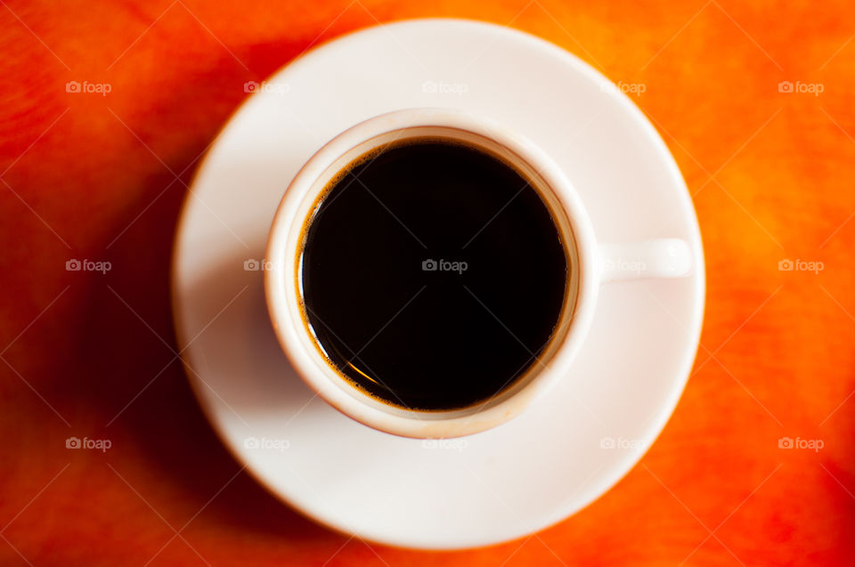 White cup of coffee on a orange background 