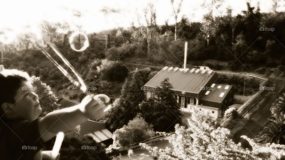 Bubbles being made by my little boy off our balcony at home. Black and white.