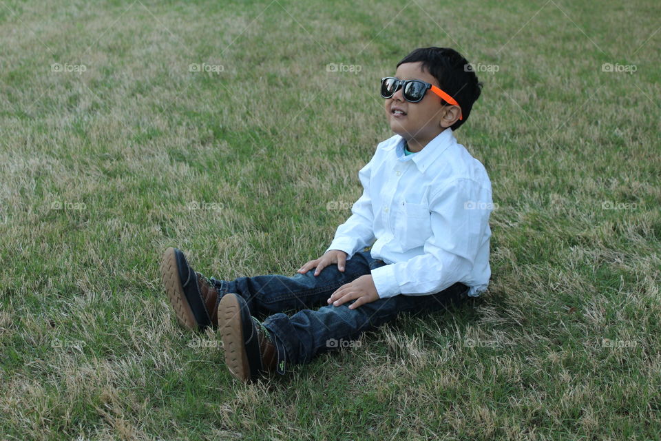 Happy kid outdoor sitting in grass 
