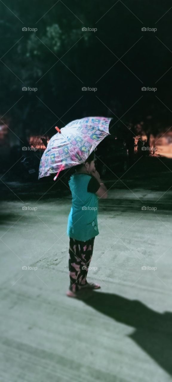 A girl standing in rain ☔ with her umbrella ☔ this is first rain in this season.
