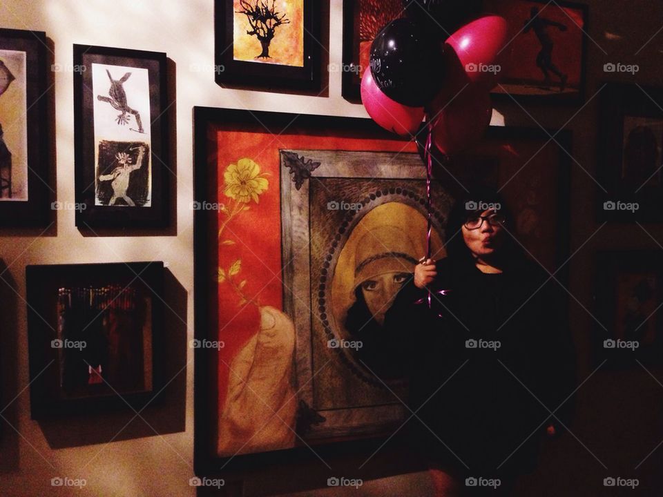 Woman with balloons next to Paintings