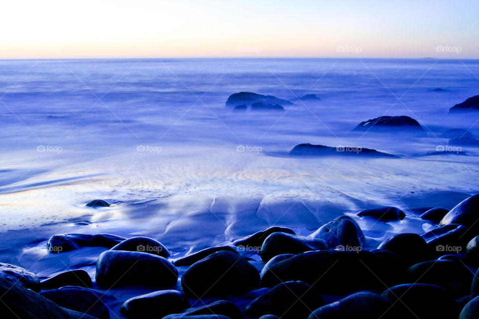 Evening landscape over the seashore with moonlight over large boulders and gentle waves. African sunset and evening.