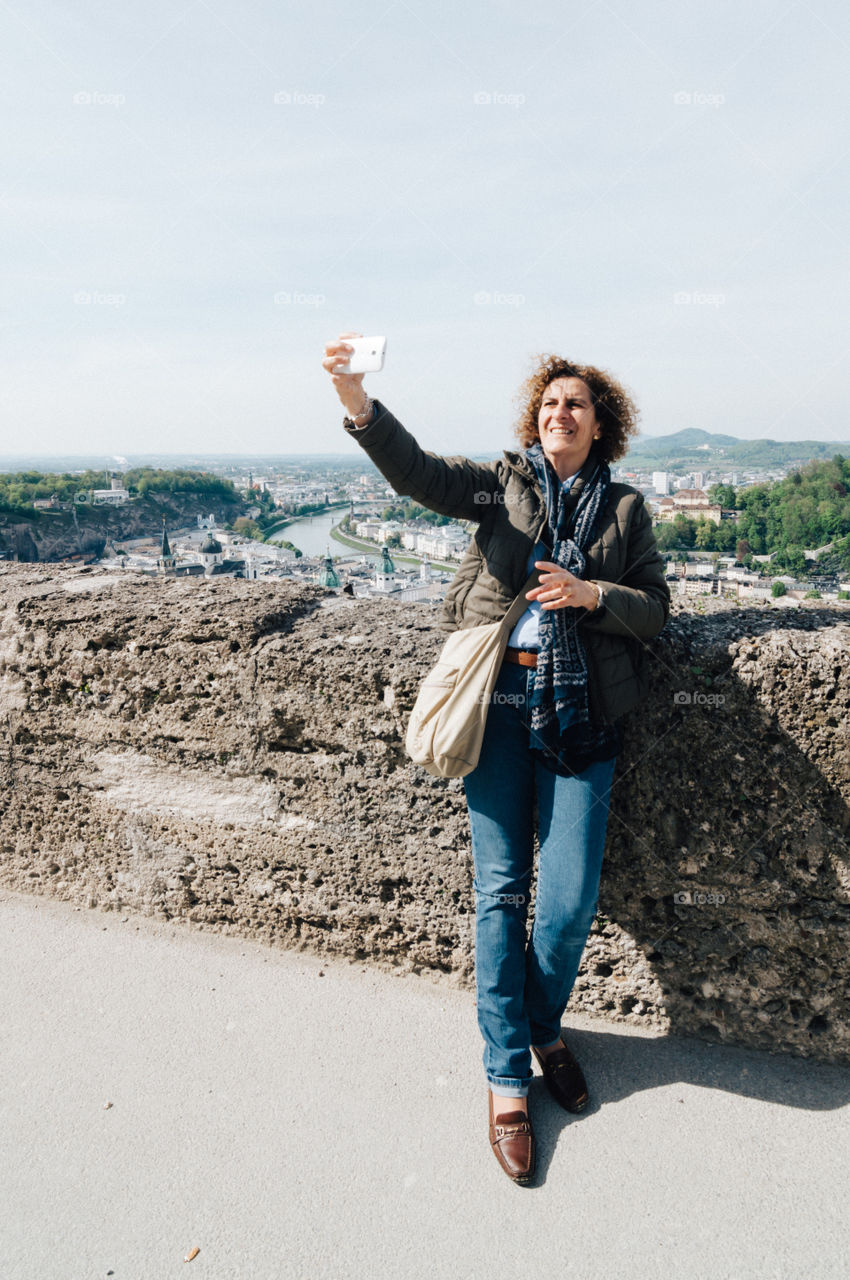Adult middle aged woman taking a selfie against Salzburg cityscape