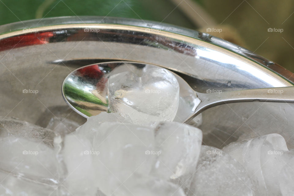 Heart shaped ice cubes in a silver bowl with a silver spoon