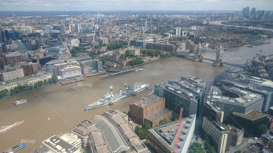 View over the River Thames on a Summer Sunday afternoon. Can see HMS Belfast, Tower Bridge and the Tower Of London. Captured from the GONG bar of the Shangri-La Hotel, on Level 52 of The Shard building, London.