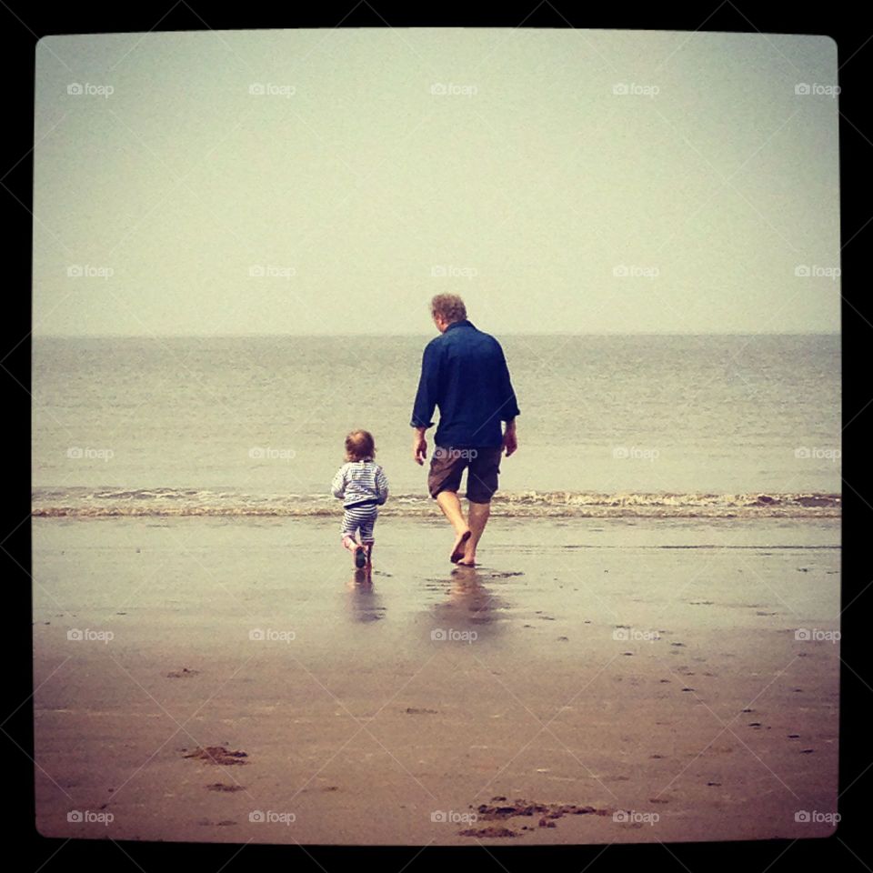 Grandfather and Granddaughter go for a paddle in early summer 