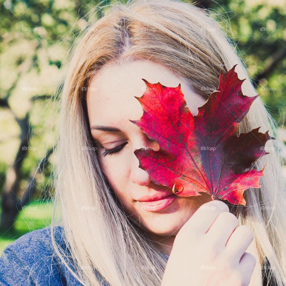 Blonde woman holding red maple leaf