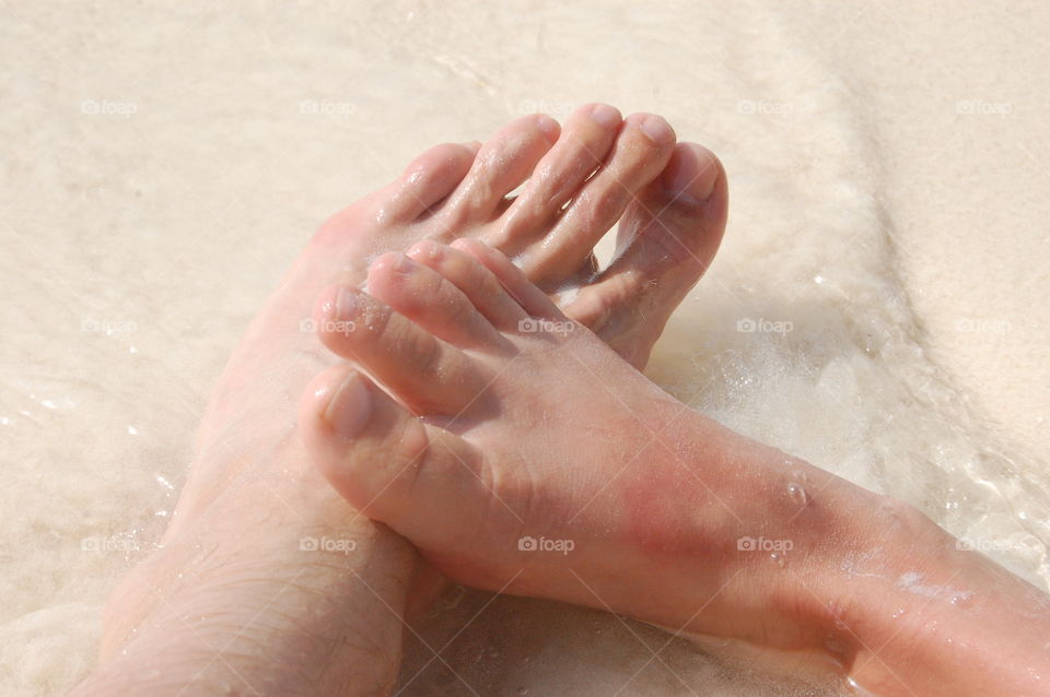 A man and woman having a romantic moment on the beach. Feet touching.