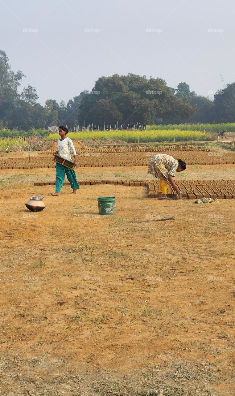 Girls working on a brick feild making bricks