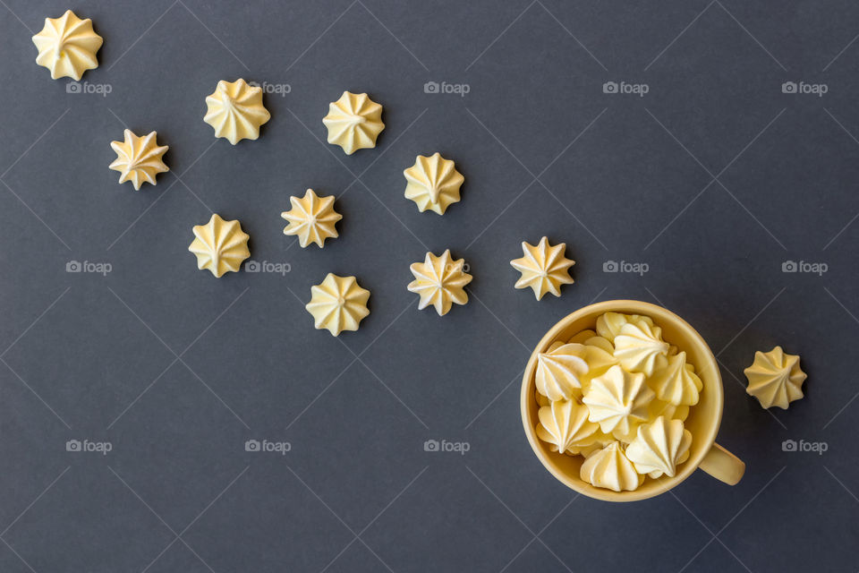 Flat lay with yellow meringue on gray background.