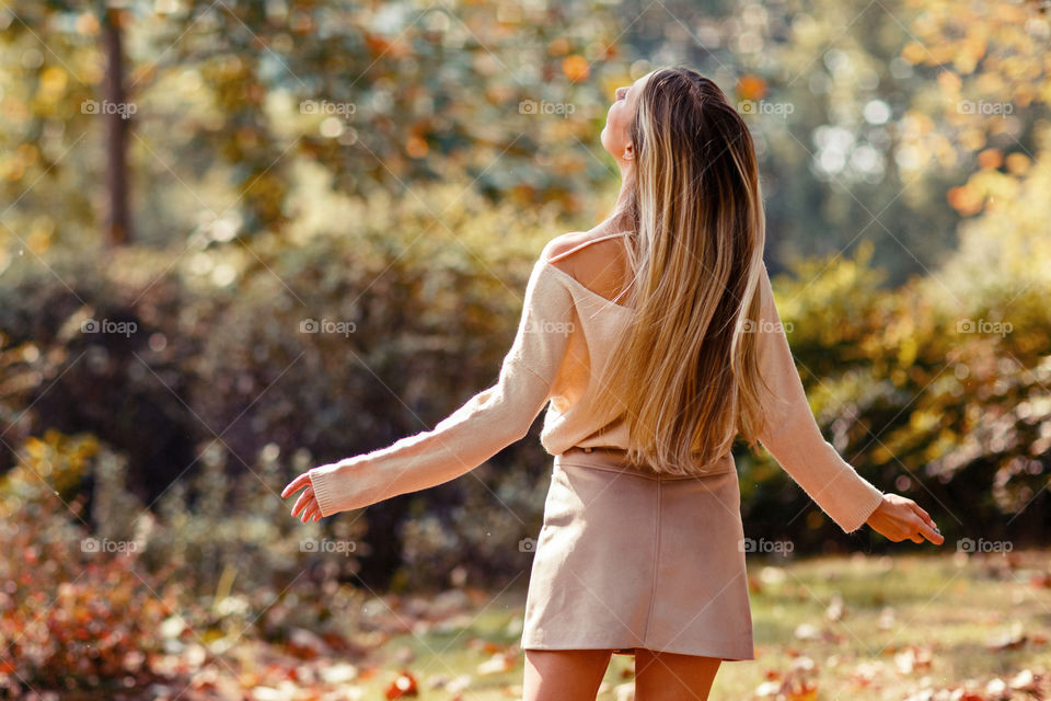 Young woman with blonde hair from behind dancing outside 