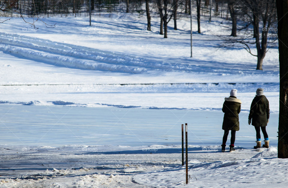 Frozen snow covered lake and mountain side on sunny day with incidental people on waters edge healthy lifestyle and outdoor activity in winter background