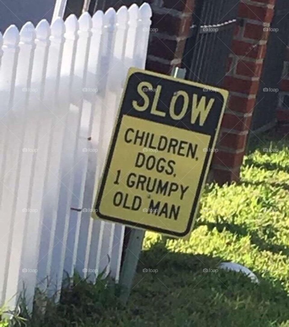 funny sign in front of old man house warning street sign next to fence in yard outside