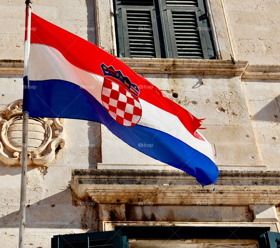 Croatian flag in Dubrovnik. Red, white and blue with central shield. On a hot, summer day