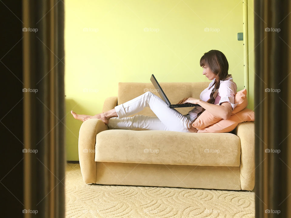 Young woman using her laptop on the cozy sofa at home 