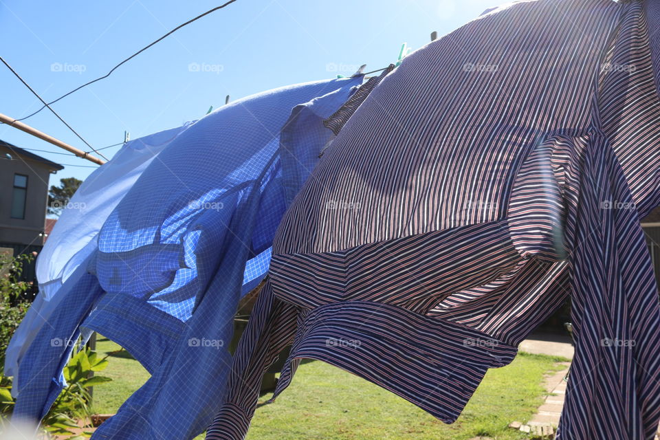 Men’s shirts drying on the laundry clothesline outdoors and blowing in the wind 