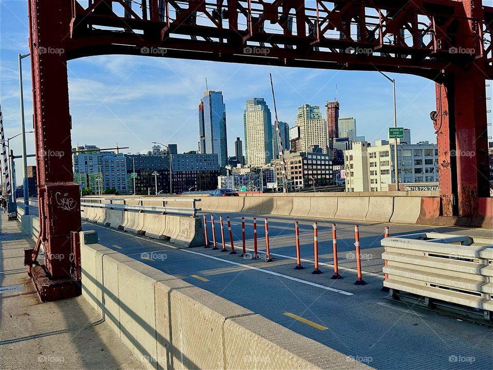 This is the „Pulaski Bridge“ at „Newtown Creek“ that connects „Greenpoint”, Bklyn to LIC, Queens in the warm golden glow of the evening sun. Nearby LIC high rises can be seen through the ornamental red metal gate. 2024. Hypnotic Productions