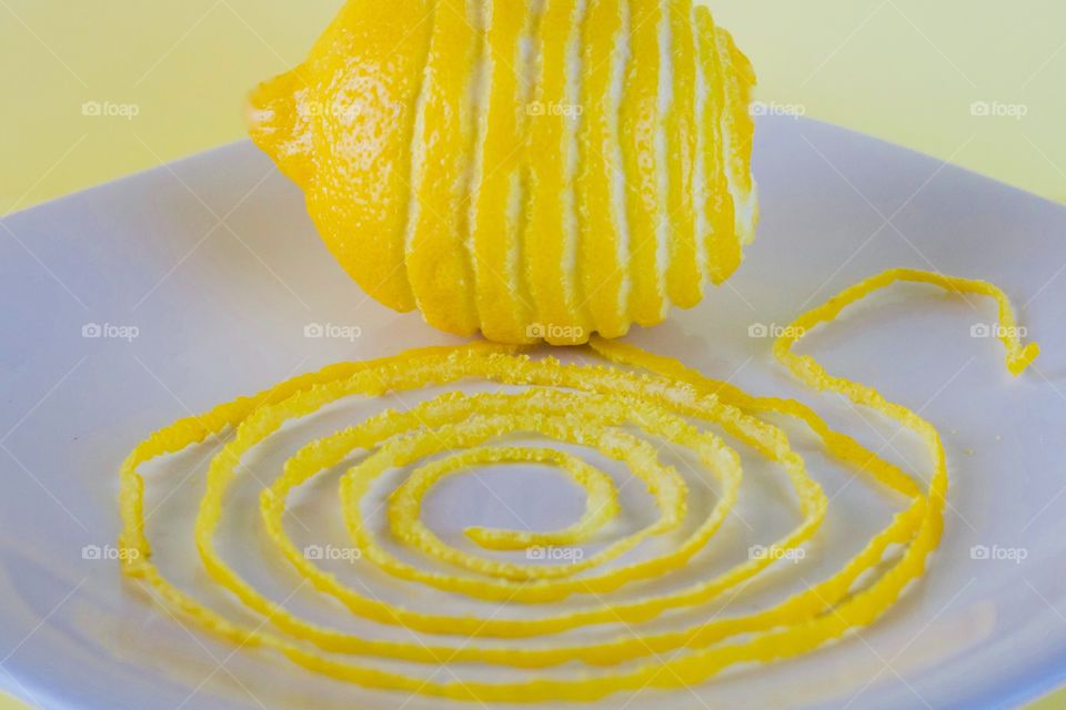 Fruits! - Lemon and spiraled lemon peel on a white plate with yellow background  