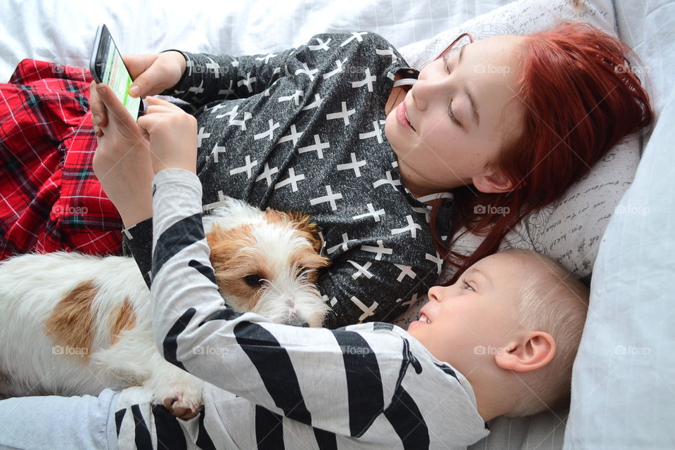 Brother and sister using smartphone with their dog