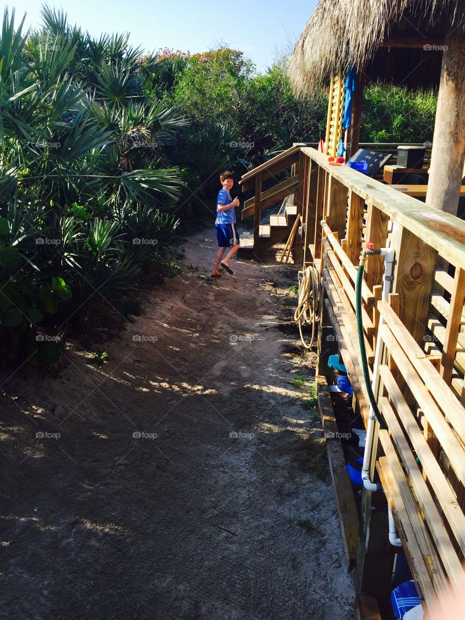 Boy running up path Florida beach 