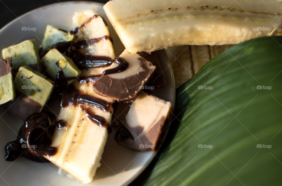 Thick chocolate sauce and fudge on plate with banana 