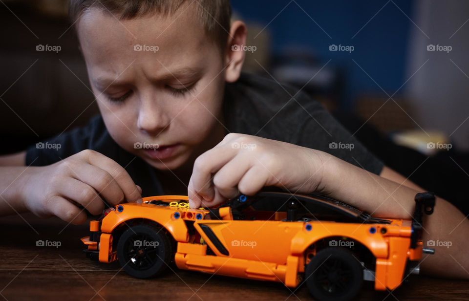 A boy assembles a race car model constructor