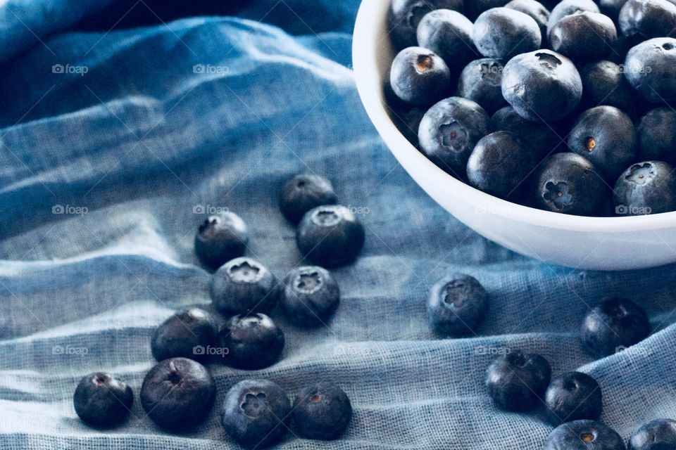 Fruits! - Blueberries in a white bowl and scattered on graduated blue fabric  