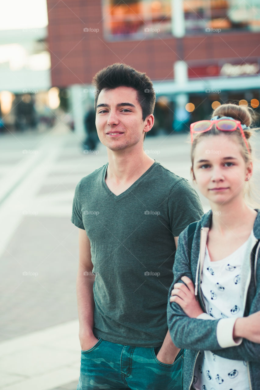 Couple of friends, teenage girl and boy,  having fun together, walking in center of town, spending time together